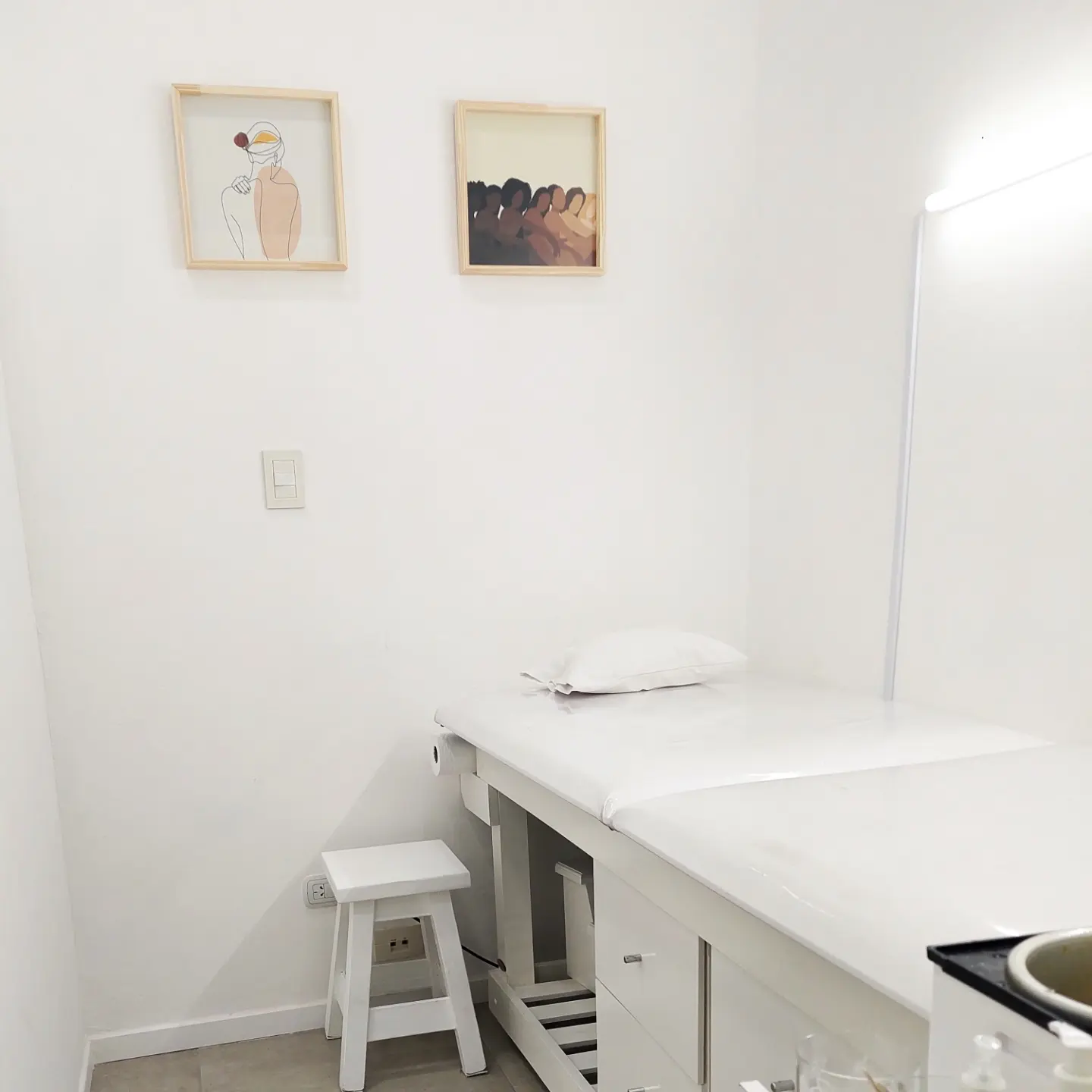 Cabina de depilación de Nala Beauty: camilla blanca, banqueta y dos cuadros en la pared