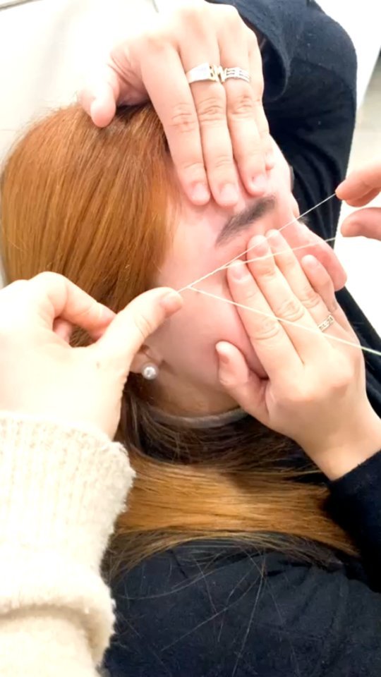 Depilación con hilo en Nala Beauty: las manos tensan el hilo sobre la ceja de una clienta